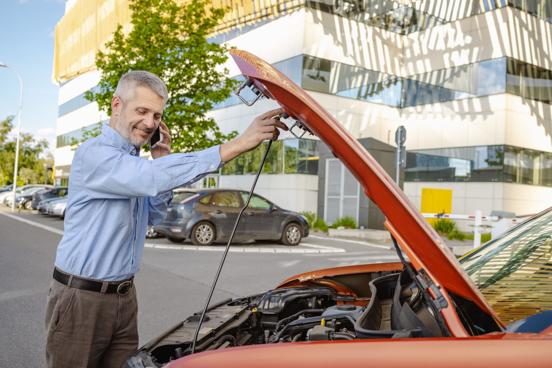 Man stranded with a broken down car using phone for help