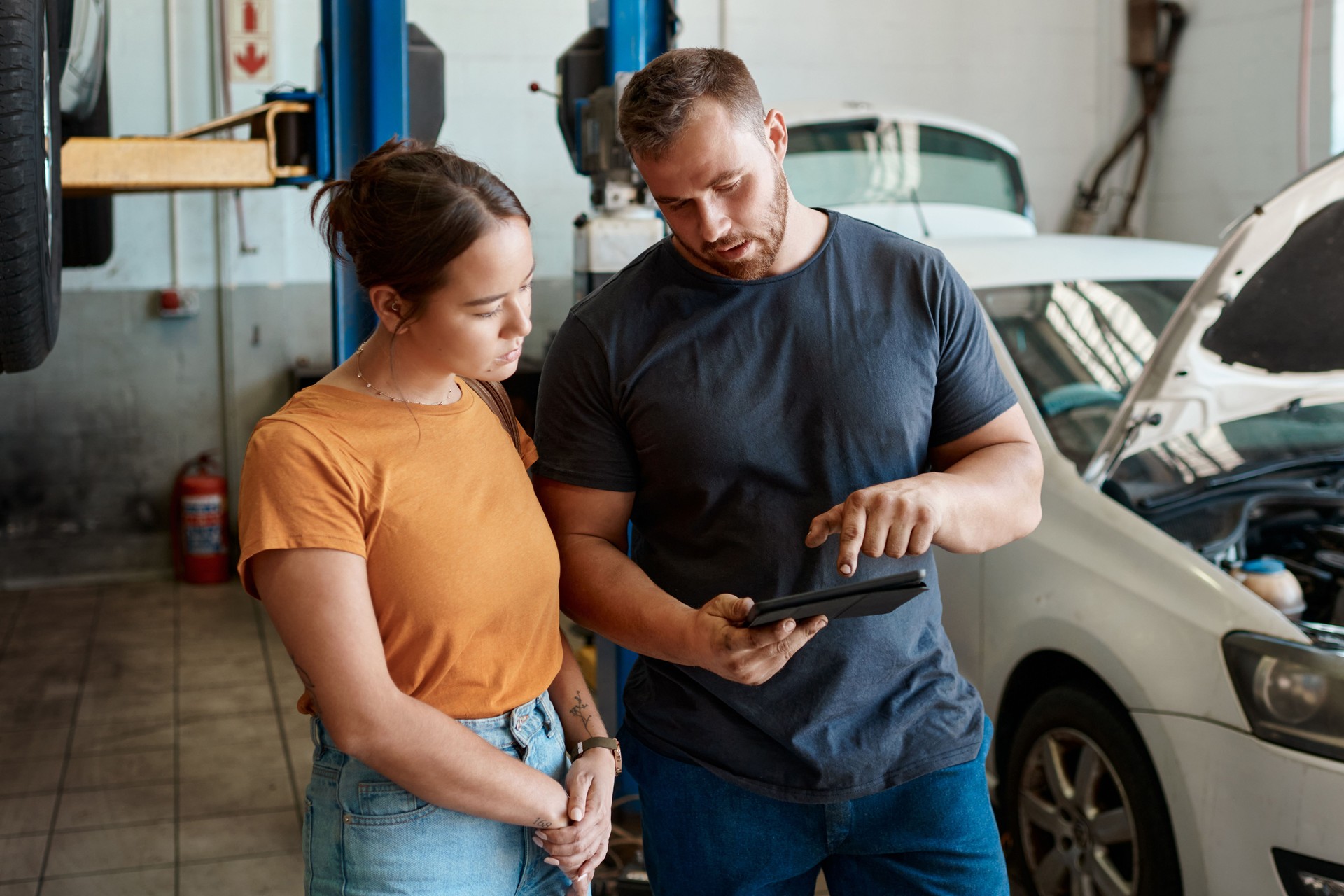 Shot of a woman talking to a mechanic in an auto repair shop