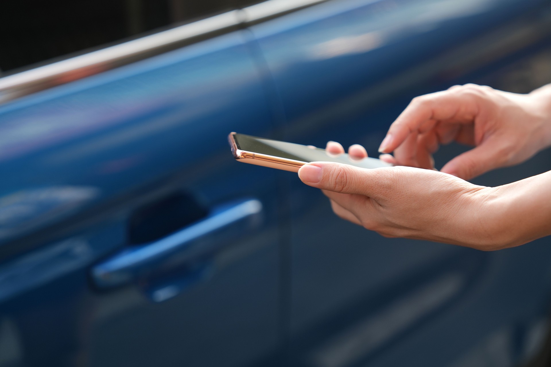 In the close-up shot, a female is seen using her smartphone while waiting for pickup on a downtown city street.